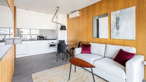 A modern living space with a white sofa, a red cushion, a wooden accent wall, and abstract art. - Centrum Mennica I (Warsaw)