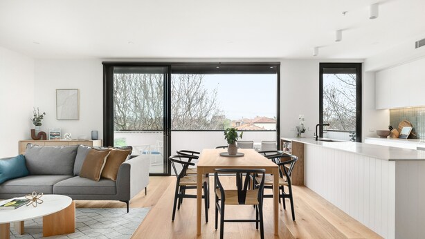 A modern kitchen with a dining area, large windows, and a view of the outside. - Docker St Elwood Apartments by UrbanRest (Elwood)