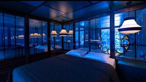 A modern hotel room with a large bed, multiple windows, and a unique stained glass window. - La Chapelle du Carmel - Centre Ville - SPA (Reims)
