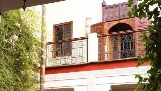 An outdoor courtyard with traditional architecture, including arches and a balcony with ornate railings. - 4 Transfert Gratuit Vers le Riad , à Votre Arrivée (Marrakech)