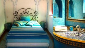 A bed with a striped blue and white bedspread, a metal headboard, and two bedside tables. - 4 Transfert Gratuit Vers le Riad , à Votre Arrivée (Marrakech)