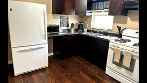 A kitchen with dark wooden cabinets, a white refrigerator, a stove, and a microwave. - A comfortable 1bed 1 bath apartment located in a quit community.  (Lakeland)