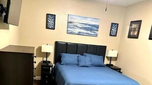 A bedroom with a bed, two bedside tables, a ceiling fan, and a painting on the wall. - A comfortable 1bed 1 bath apartment located in a quit community.  (Lakeland)