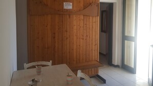 A dining area with a wooden partition, a table with chairs, and a sign on the partition. - Trilocale Mimose in Baia Verde (Gallipoli)