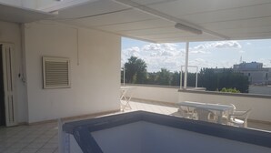 A balcony with a view of the sky and trees, a white door, and a window with blinds. - Trilocale Mimose in Baia Verde (Gallipoli)