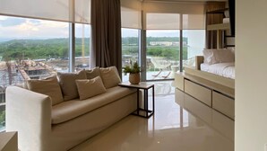 A modern living room with a large window, a sofa, a small table, and a staircase. - Eco by Wynwood House (Cartagena)