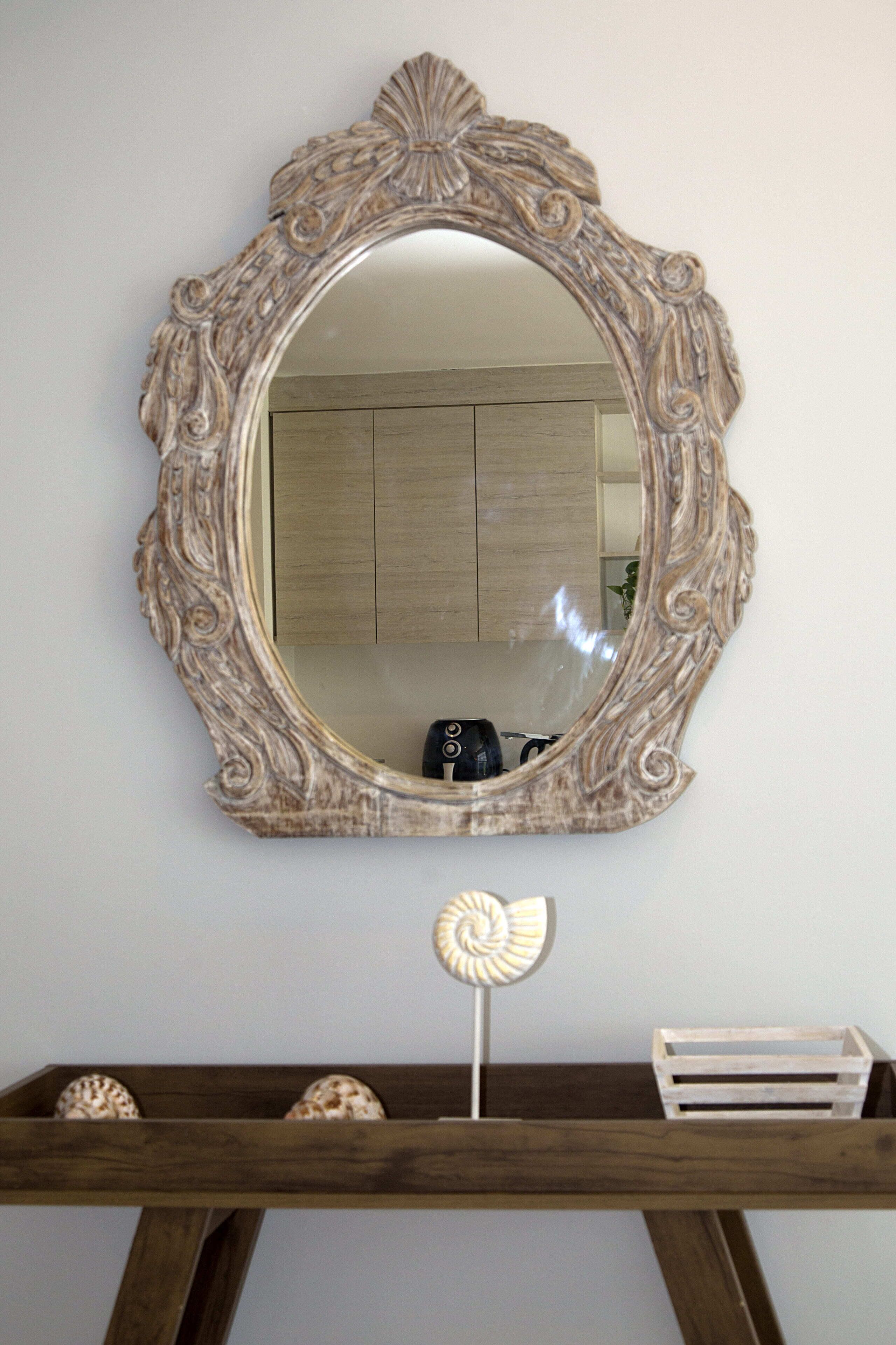 Un miroir avec un cadre orné, accroché au mur.