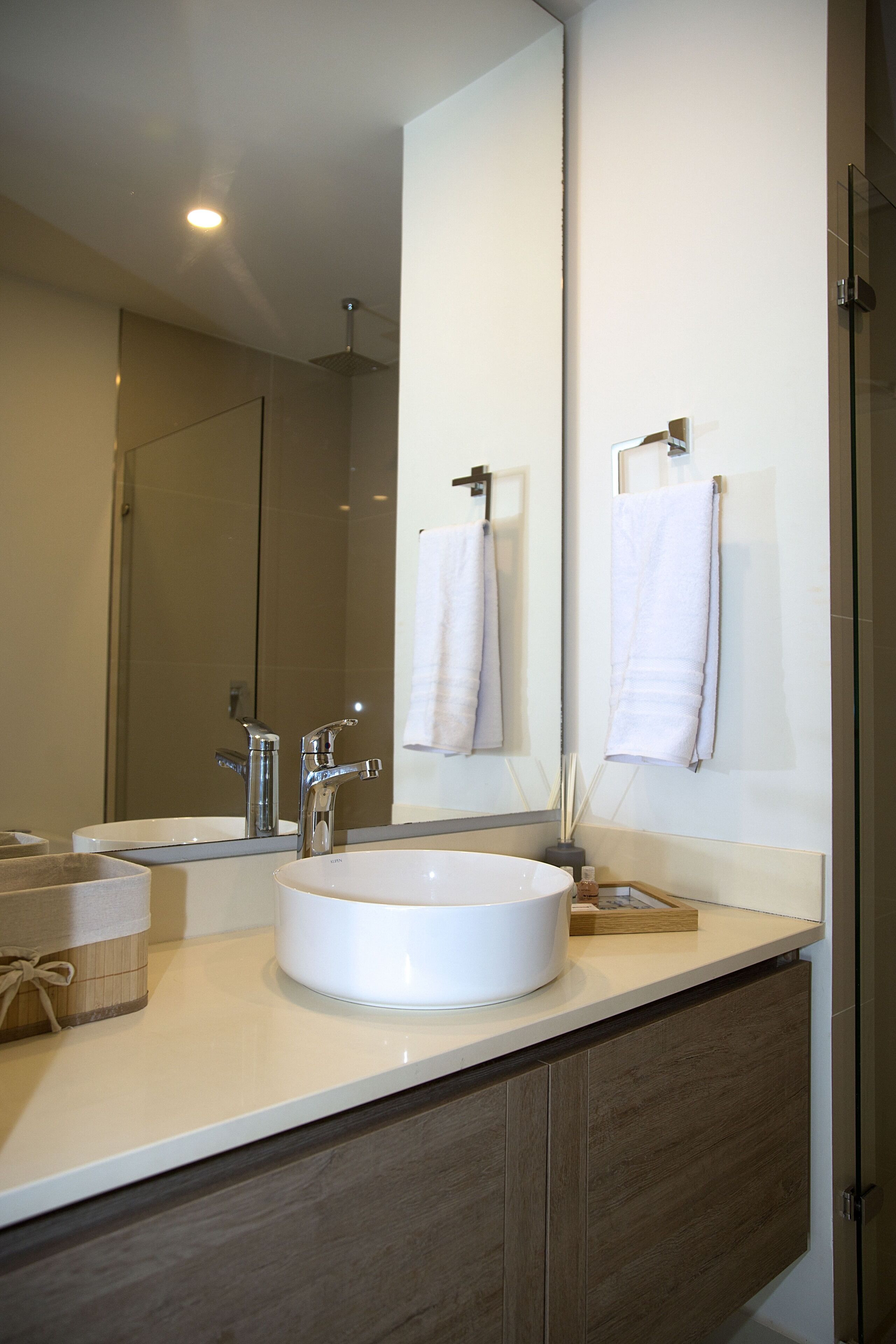 A modern bathroom with two sinks, a large mirror, and a towel rack.