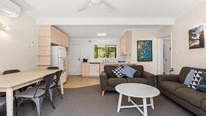 Un apartamento moderno con comedor, sala de estar con sofá y mesa de centro, cocina con ventana y un mapa en la pared.