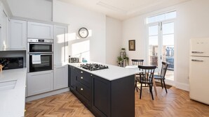 Una cucina moderna con mobili bianchi, piano cottura a gas e un'area pranzo con due sedie.