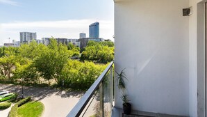 En balkong med utsikt över en stadsbild, inklusive moderna byggnader och frodig grönska.