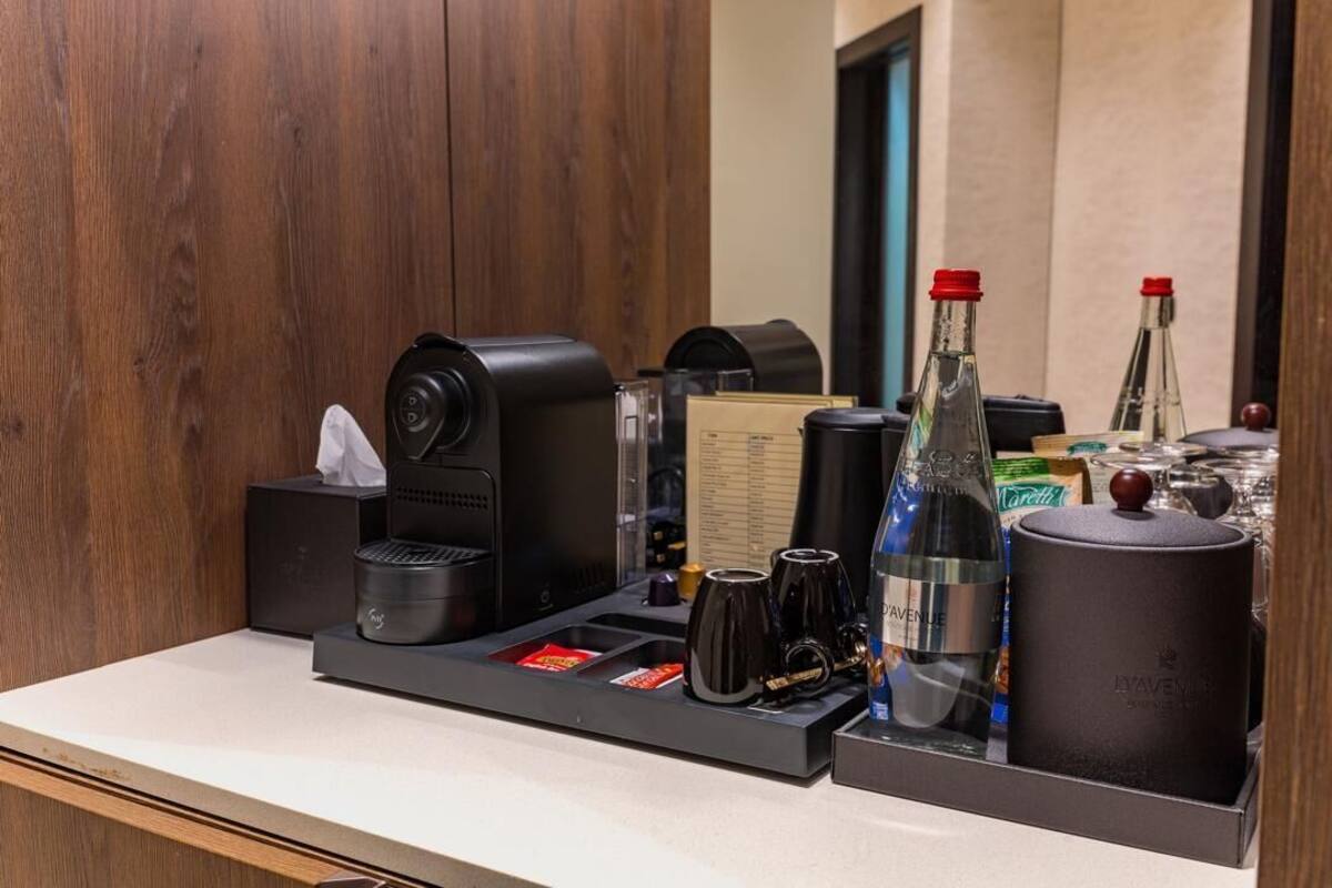 De minibar in een hotelkamer, met een koffieapparaat, een fles wijn en diverse glazen.