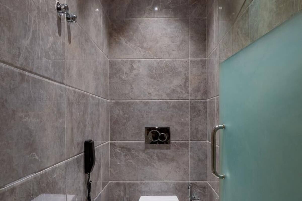 Een moderne badkamer met toilet, hygiëneschuimer en handdroger.