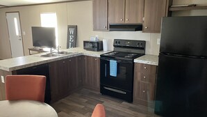 A compact kitchen with wooden cabinets, a black stove, a microwave, and a refrigerator.