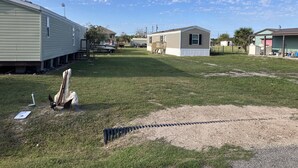 A residential area with mobile homes, a grassy yard, and a gravel path.