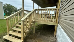 A wooden deck with a staircase leading to a covered area.