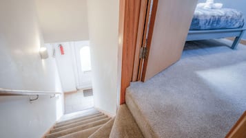 A carpeted staircase leading to a bedroom with a bed and a wooden door.