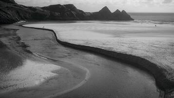 A beach with a curved shoreline, rocky outcrops, and a distant view of the ocean.