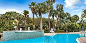 A swimming pool surrounded by palm trees, a fountain, and lounge chairs. - Ocean View Home with Pool in Gated Community - 1 Min Walk to Ocean (Destin)