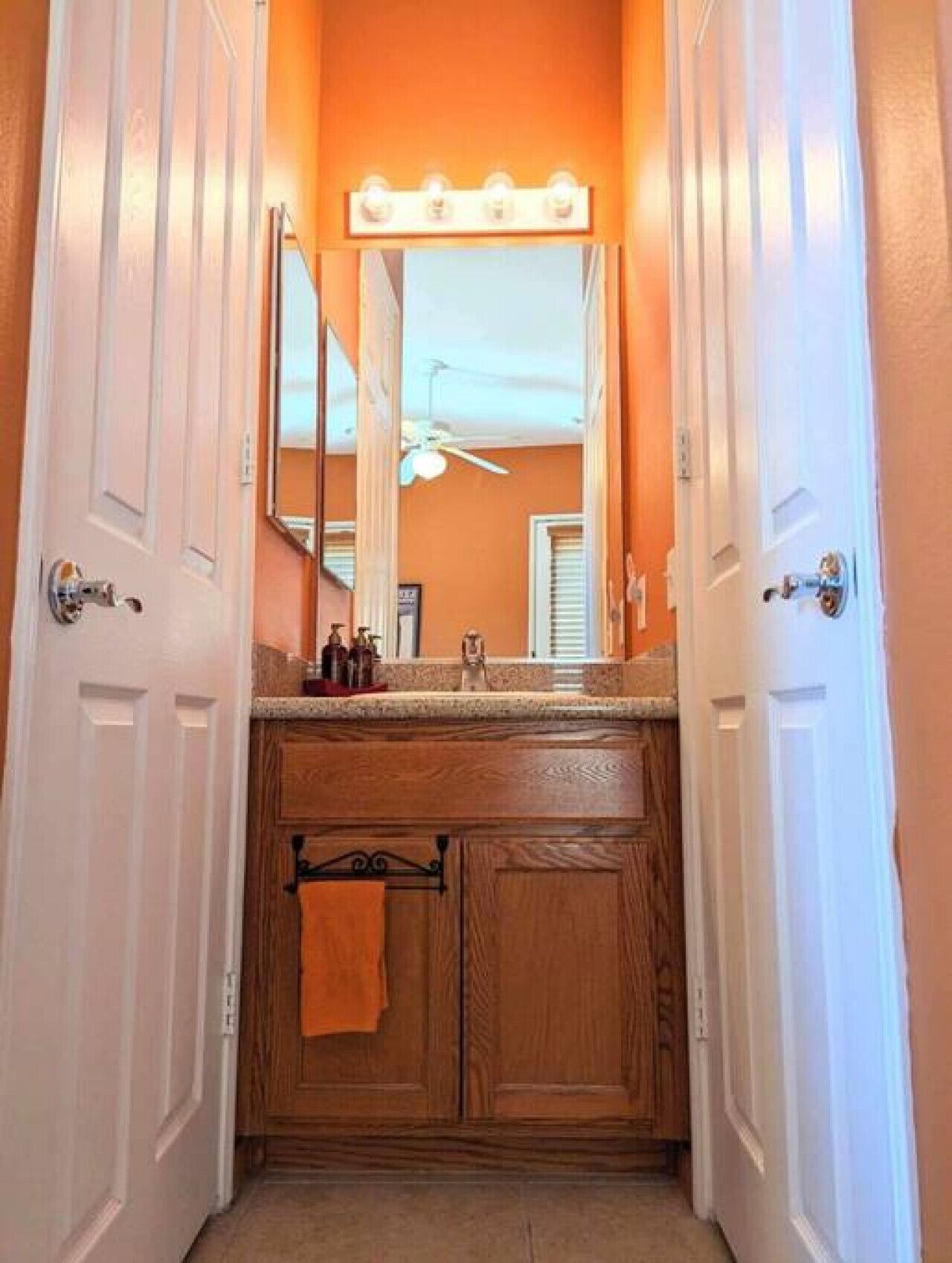 A narrow hallway with a wooden vanity and a mirror above the sink.