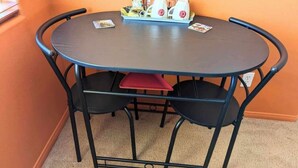 Ein runder Tisch mit vier Stühlen, einem roten Kissen und einer Ablage mit Kaffeemaschine und Tassen.
