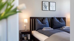 A hotel room with a bed, a nightstand with a lamp, and two framed artworks on the wall. - Apartment Bianca Superior (Salzburg)