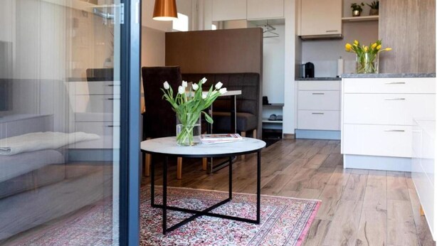 A modern kitchen with white cabinets, a dining area with a round table, and a living space with a sofa and a coffee table. - Apartment Bianca Superior (Salzburg)