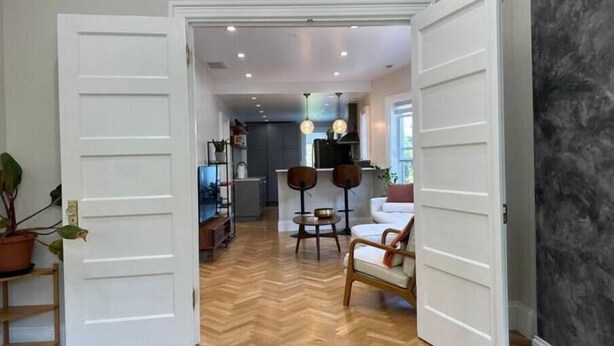 An open-plan living area with a herringbone wood floor, a kitchen in the background, and a dining area with two chairs and a table. - Have a Spring Fling or Work Remote - Hi Speed  WIFI! (Chicago)