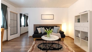 Un salon moderne avec un canapé foncé, une table basse ronde et un tapis à motifs.