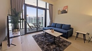 Una sala de estar moderna con un sofá azul, una mesita de centro, un ventanal con cortinas y vistas a la ciudad.
