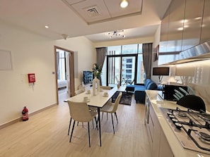 Una cocina moderna con estufa a gas, comedor con sillas, sofá y televisor.