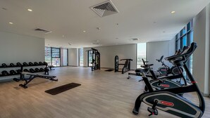 Un gimnasio moderno con equipo de cardio, estaciones de levantamiento de pesas y un amplio ventanal que proporciona luz natural.