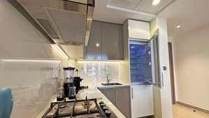 Una cocina moderna con estufa a gas, licuadora y refrigerador.