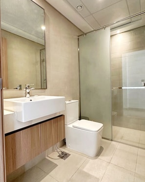 Un baño moderno con lavamanos, espejo y retrete blancos.