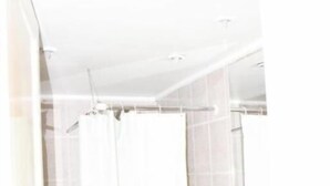 Une salle de bain avec un lavabo blanc, un rideau de douche et des murs carrelés.