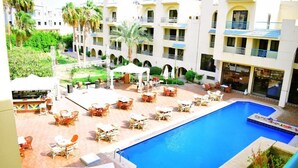 A hotel courtyard with a swimming pool, outdoor seating, and multiple balconies. - Single Room LA
الغردقه
ميدان المحمدي الهضبه اول الممشى السياحي
 (Hurghada)