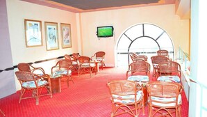A room with wicker chairs and tables, a television on the wall, and a large arched window. - Single Room LA
الغردقه
ميدان المحمدي الهضبه اول الممشى السياحي
 (Hurghada)