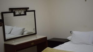 Een hotelkamer met een bed, nachtkastje, spiegel en een wandlamp.
