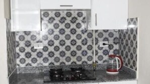 Een keuken met witte kasten, een decoratieve spatwand en een gasfornuis.