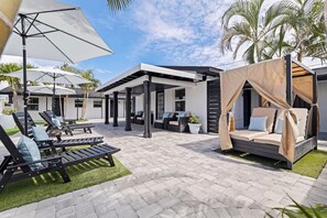 A modern outdoor lounge area with sun loungers, a covered seating area, and a canopy bed. - Las Olas of Treasure Island No. 1 (Treasure Island)