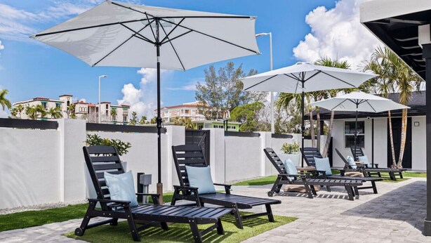 Een terras met buitenmeubilair, parasols en uitzicht op de omliggende gebouwen.