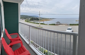 Enjoy the serene coastal views from this balcony, featuring a comfortable seating area and a glimpse of the nearby shoreline.