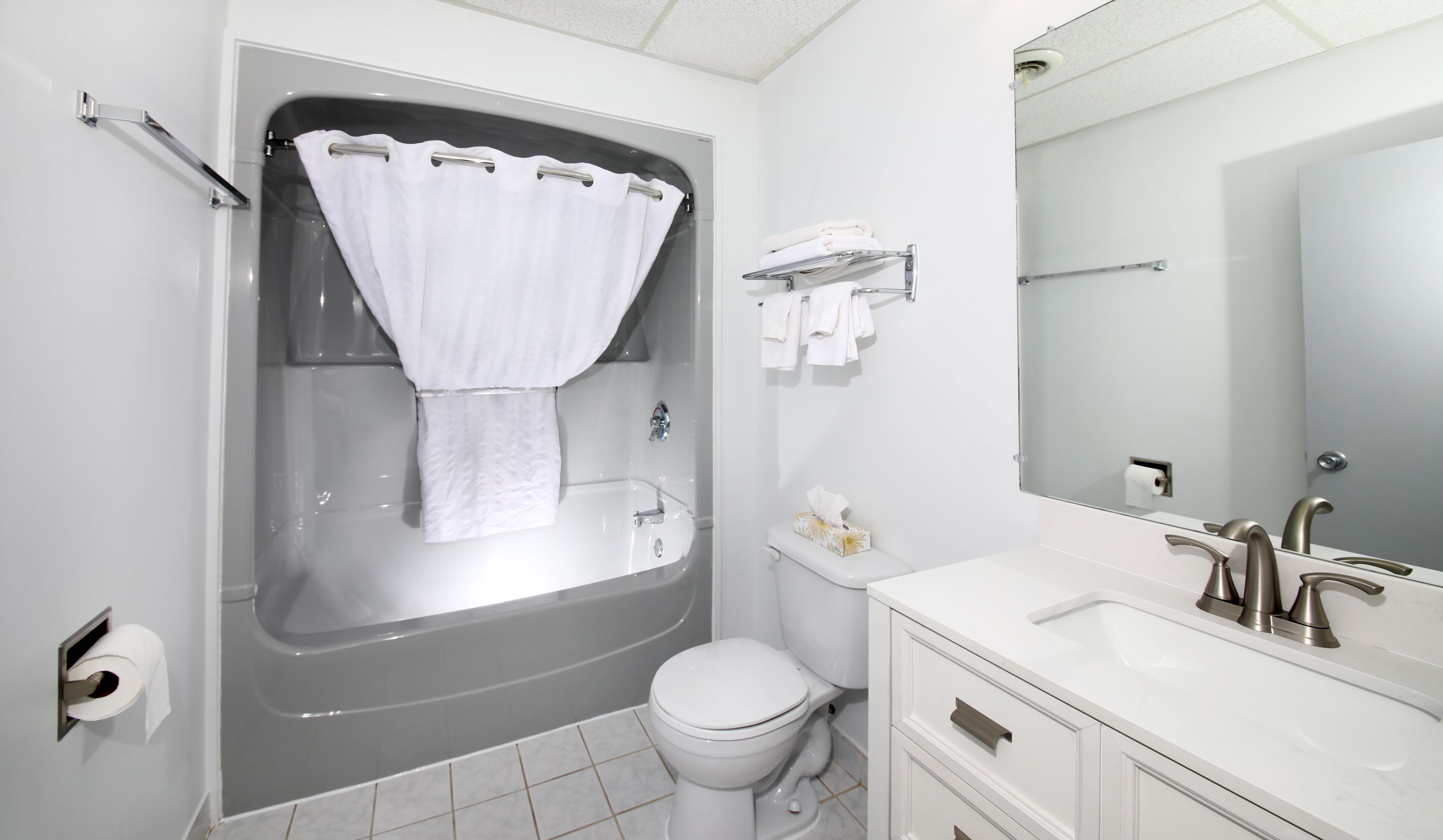 A modern bathroom with a bathtub, toilet, and vanity.