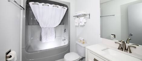 A modern bathroom with a bathtub, toilet, and vanity.