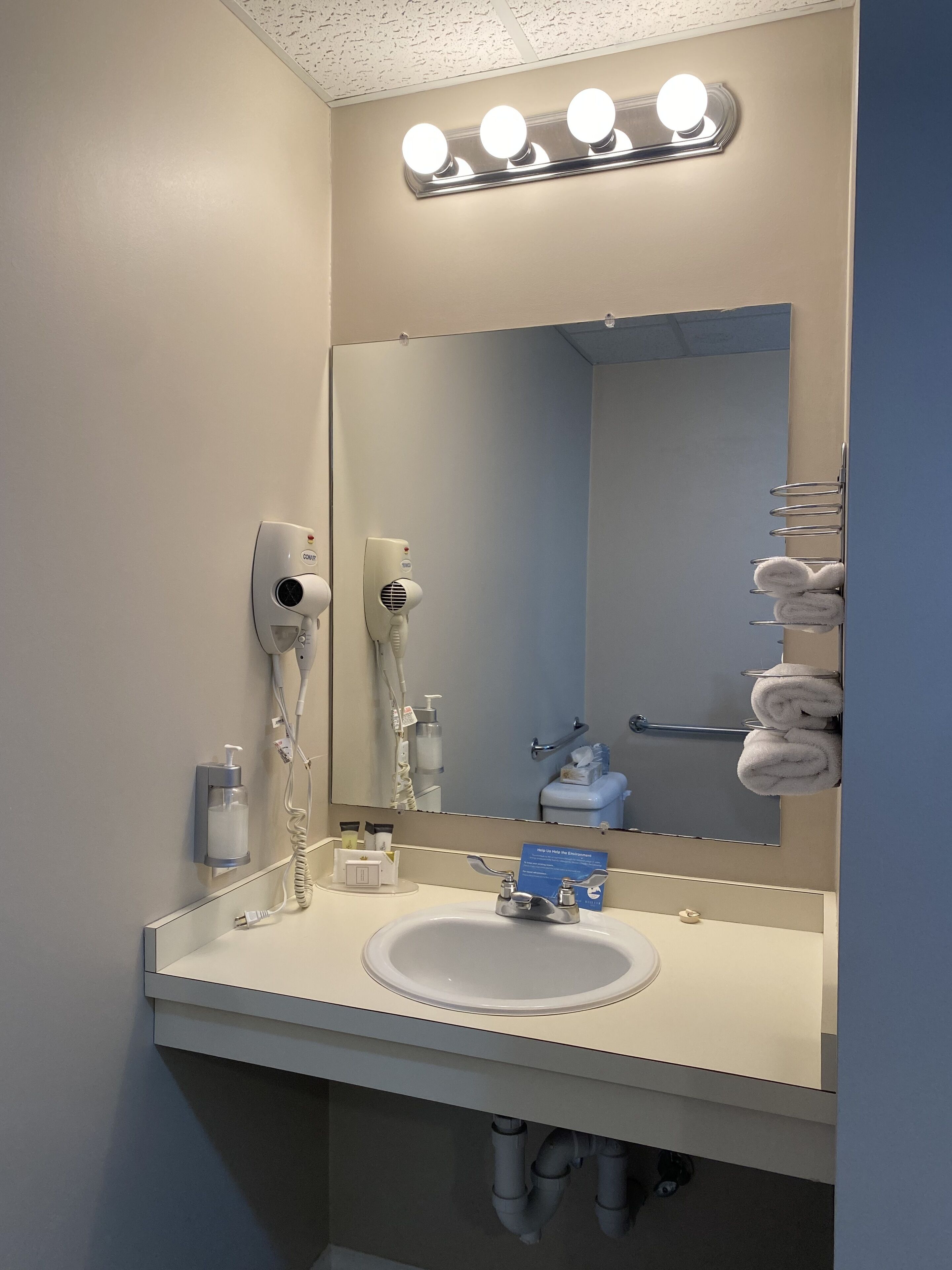 A bathroom with a sink, mirror, towel rack, and hairdryer.