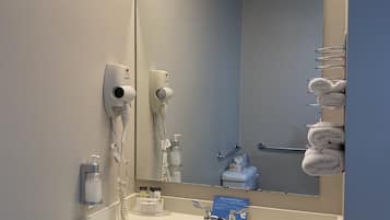 A bathroom with a sink, mirror, towel rack, and hairdryer.