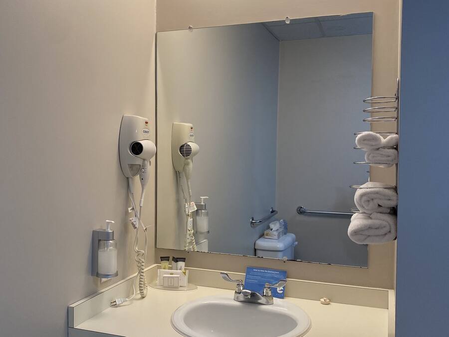 A bathroom with a sink, mirror, towel rack, and hairdryer.