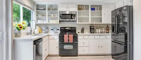 A modern kitchen with white cabinetry, a built-in oven, a microwave, and a refrigerator.