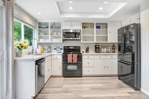 A modern kitchen with white cabinetry, a built-in oven, a microwave, and a refrigerator.