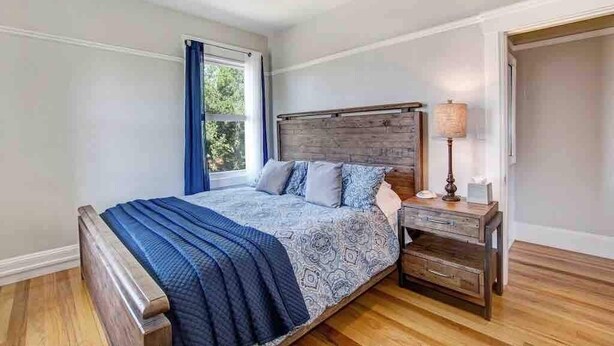 A bedroom with a bed, a nightstand, a lamp, a window with curtains, and a ceiling fan. - Casa Bella Estate in Wine Country w/ New Pool! (Kenwood)